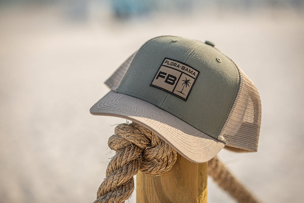 green and tan hat with palm tree and Flora bama sitting on rope