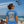 Woman on a beach wearing a blue t-shirt with a patriotic design, airplanes flying overhead.