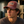 Man wearing a maroon and beige cap with 'Flora-Bama' logo, sitting outdoors.