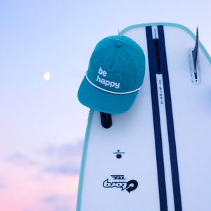 blue beach happy hat on a surfboard