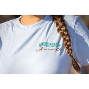 Person wearing a light blue t-shirt with 'Flora-Bama America 250' text, standing outdoors.