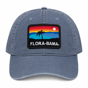 Blue cap with a 'Flora-Bama' patch featuring a palm tree and sunset design 