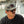 Man wearing a camouflage cap and sunglasses with a blurred background