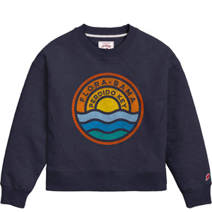 A navy Flora-Bama ladies boxy crewneck sweatshirt with a graphic design featuring the name 'Flora-Bama' and a sun and water circle logo.