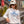 woman wearing a beige hoodie with the Flora-Bama text across the front with waves and sun and a white flora bama hat with colorful patch