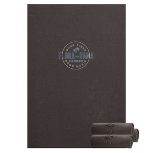 Dark gray blanket with 'Flora-Bama' logo and rolled-up towel on a white background