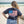 person wearing a navy blue t-shirt with a graphic of the American flag and the 'Flora-Bama' logo on it.