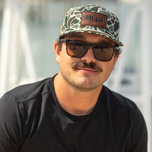 Man wearing sunglasses and a cap with a blurred background