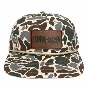 Camouflage-patterned cap with a brown leather patch displaying 'Flora-Bama' 