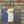 three shirts - A gray, white and blue Flora-Bama brand t-shirt with a wavy yellow logo on the front.