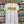 A white Flora-Bama brand t-shirt with a wavy yellow logo on the front hanging on license plates
