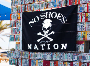 Flag with 'No Shoes Nation' design on a background of license plates.