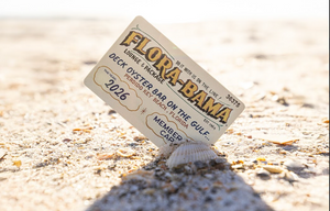 flora bama membership card propped on a shell in the sand
